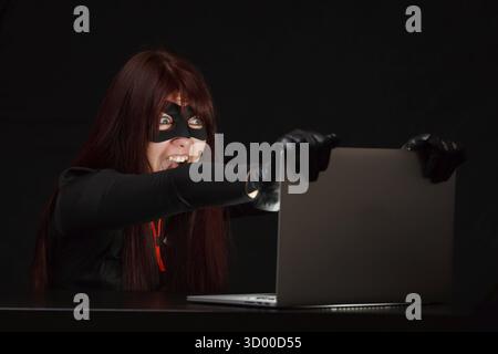 Hacker in black mask at night near computer Stock Photo