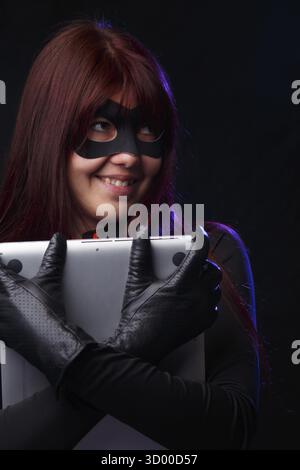 Happy thief in black gloves holds laptop Stock Photo