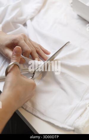 Woman tailors with scissors cloth on table close-up Stock Photo