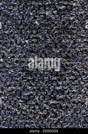 Abstract dark crumpled plastic texture with glowing light reflections creating a metallic and futuristic effect. Shiny surface and intricate folds for Stock Photo