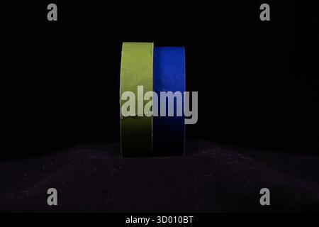 two multicoloured rolls of decorators masking tape isolated on a black background Stock Photo