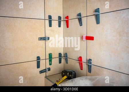 Conical plastic tile leveling system clips and wedges help tools for leveling as install between the tiles with spacer among them Stock Photo