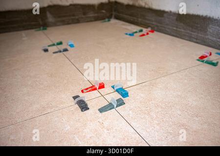 Conical plastic tile leveling system clips and wedges help tools for leveling as install between the tiles with spacer among them Stock Photo