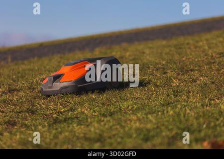 Husqvarna robotic lawn mower stands ready to automatically trim a suburban green grass field. High quality photo Stock Photo