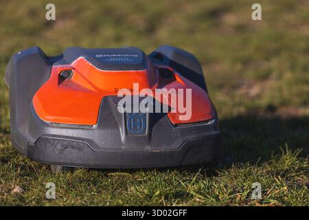 Husqvarna robotic lawn mower stands ready to automatically trim a suburban green grass field. High quality photo Stock Photo