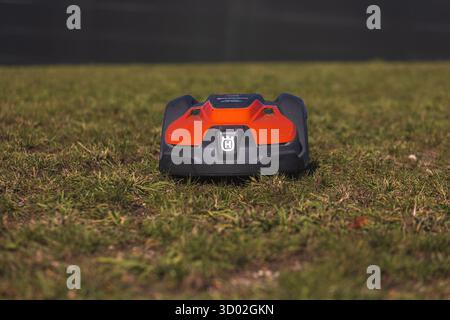 Husqvarna robotic lawn mower stands ready to automatically trim a suburban green grass field. High quality photo Stock Photo