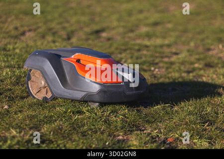 Husqvarna robotic lawn mower stands ready to automatically trim a suburban green grass field. High quality photo Stock Photo