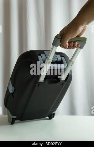 Portrait frame of suitcase being pulled from side view, traveler in motion against clean white cloth background, dynamic travel lifestyle presentation Stock Photo