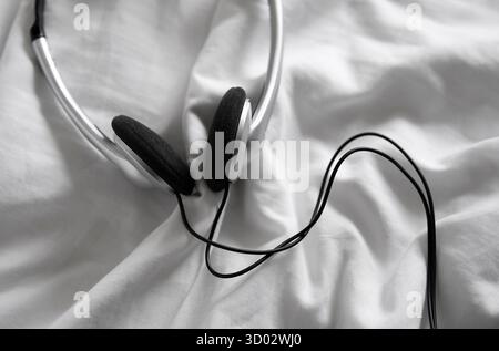 headphones on white crumpled bed sheet Stock Photo