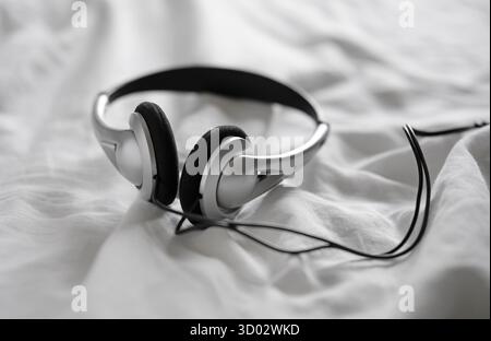 headphones on white crumpled bed sheet Stock Photo