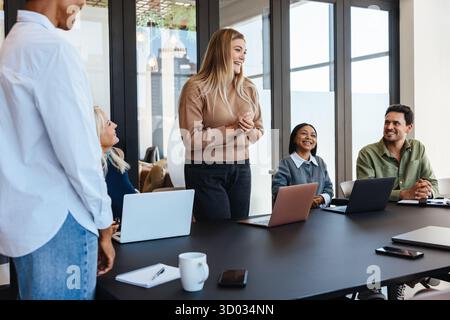 A diverse group of people having a productive discussion in a conference room. They exchange ideas while using laptops. Engagement, teamwork, and coop Stock Photo