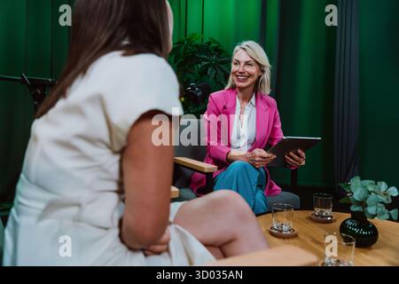 Group of three individuals engaging in a dynamic conversation during a recording session in a professional podcast studio, broadcasting with microphon Stock Photo