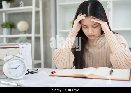 Asian student woman have anxiety because of exams, female prepare for test and learning lessons in the library. stress, despair, haste, misunderstandi Stock Photo