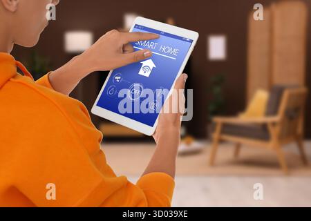 Man using smart home app on tablet computer in room, closeup Stock Photo