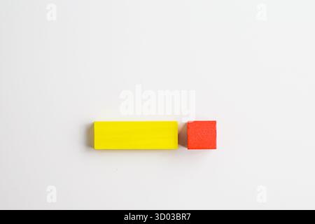 Two colorful wooden blocks, one yellow rectangular and one red square, placed side by side on a clean white background in a minimalist, isolated compo Stock Photo