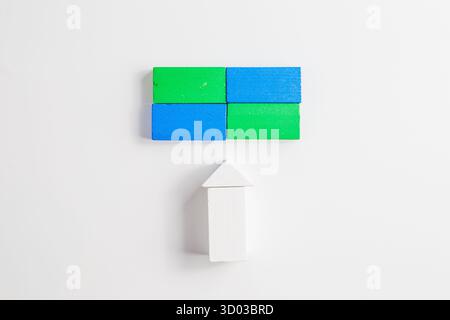 Four rectangular blocks in blue and green form a base, topped with a white wooden arrow pointing upward, arranged on a white background in a minimalis Stock Photo