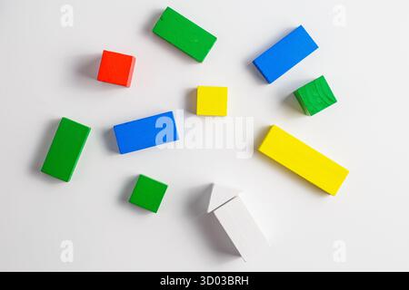 Multiple colorful wooden blocks in various shapes, including rectangles, squares, and one white arrow, randomly arranged on a clean white background. Stock Photo