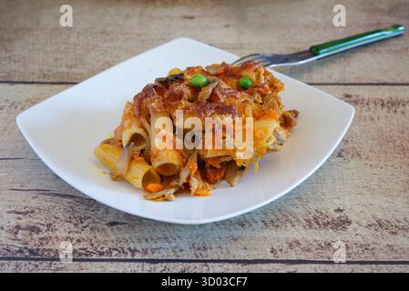 Rigatoni pasta baked with pumpkin, mushrooms, peas, and melted cheese on a white plate Stock Photo