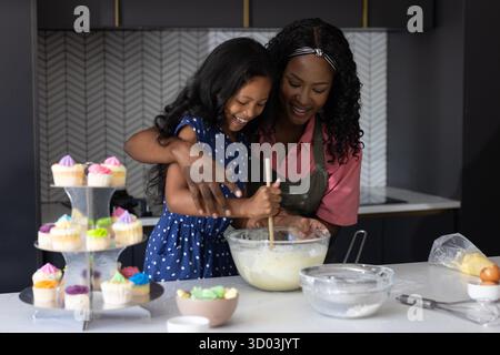 Baking cupcakes, mother and child sharing joyful moment in modern kitchen together. Family, bonding, cooking, homemade, dessert, happiness || Model released Stock Photo
