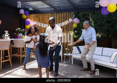 Celebrating birthday outdoors, family dancing with colorful balloons and decorations. Celebration, party, joy, festive || Model released Stock Photo
