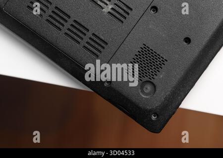 Upside down black laptop with cooling vents and screw mounts on white table Stock Photo