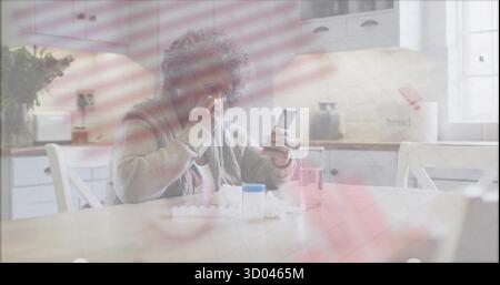 Holding smartphone and dabbing nose, senior woman sitting at home kitchen table, with pill bottle Stock Photo