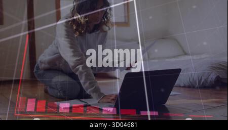 Typing woman in hoodie and jeans on black laptop in small bedroom, with documents and notebook Stock Photo