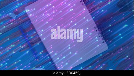 Displaying spiral-bound notebook on blue desk with USB drive, cable, tape amid light streaks Stock Photo