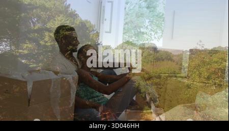 Smiling couple leaning back on couch in living room, with moving boxes and glass sliding door Stock Photo