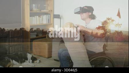 Man in wheelchair using VR headset and controller in living room, dogs, forest overlay, copy space Stock Photo