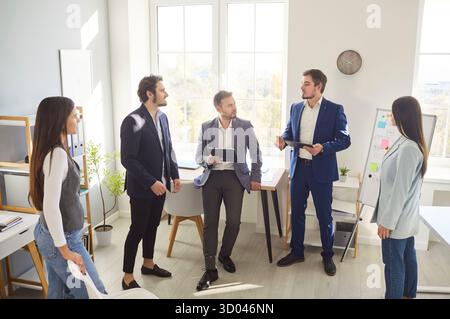 Young professionals discussing business strategies in office with man presenting ideas to colleagues Stock Photo