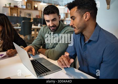 Two creative multiracial coworkers working together on laptop at modern office Stock Photo