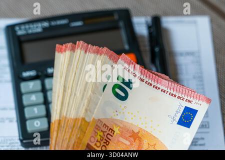 Stack of ten euro banknotes placed on a table with a calculator and documents, representing finance, budgeting, banking, and accounting concepts Stock Photo