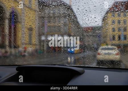 Raindrops on glass with blurred city buildings and cars Stock Photo