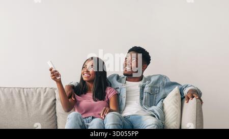 Young black woman switching on air conditioning at her home Stock Photo