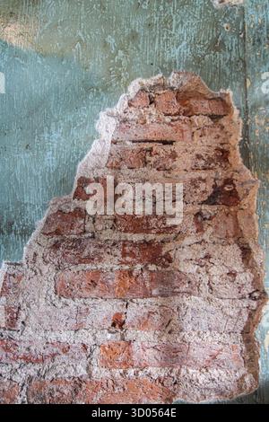 Distressed brick wall texture with peeling teal/aqua plaster. Rough grunge background for architectural detail, history, or urban decay concepts. Stock Photo