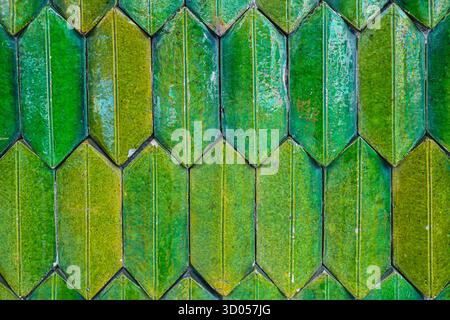 Glossy green & yellow ceramic tile texture in a vertical herringbone pattern. Thai temple architectural detail, perfect for abstract background design. Stock Photo