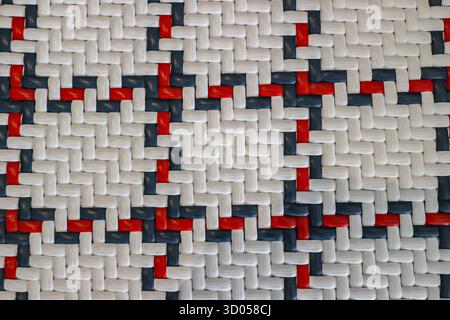 Close-up abstract texture of woven plastic straps in a white, red, and blue checkered pattern. Detailed geometric background for digital design. Stock Photo