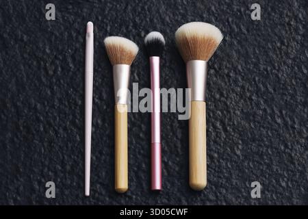 Makeup brushes set on dark background. Cosmetic tools for face and eyes. Beauty accessories flat lay. Professional makeup equipment. Stock Photo