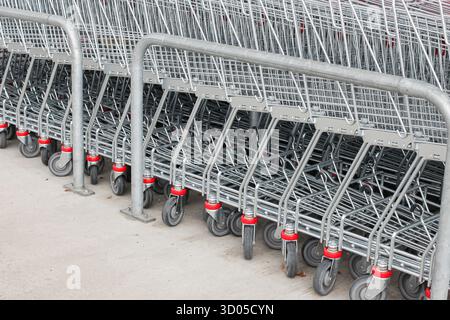 Shopping carts lined up outside supermarket. Retail and consumerism concept with metal trolleys in parking area. Stock Photo