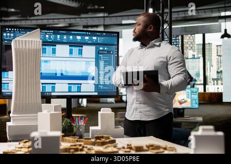 Black real estate professional uses architectural software to create a vision for a smart city infrastructure, focusing on apartment construction, property investment and zoning regulations. Stock Photo