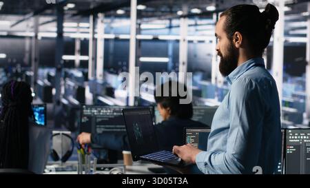 Server room technician using AI LLM chatbot to review infrastructure diagnostics. IT expert in data center using artificial intelligence large language model to analyze performance data, camera A Stock Photo