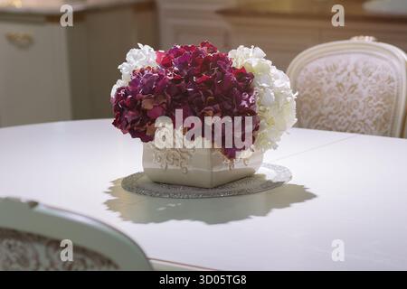Elegant dining table centerpiece hydrangea flowers ornate vase in classic interior Stock Photo