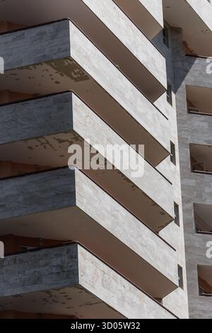 View of stark, horizontal balconies jutting from a textured concrete facade create a rhythmic, repeating pattern of shadow and light, Yerevan, Yerevan, Armenia. Stock Photo