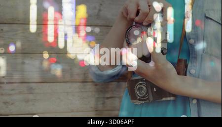 Asian photographer adjusting lens on film camera with leather strap against plank wall, copy space Stock Photo