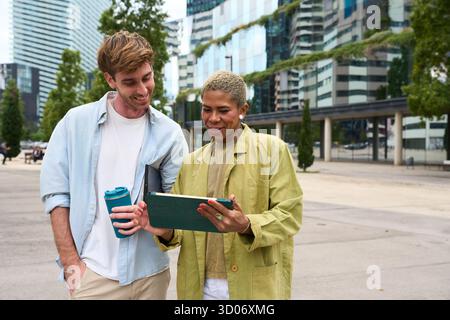 Diverse colleagues collaborating using digital tablet outdoors in city Stock Photo