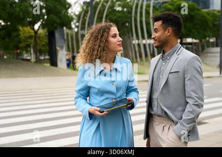 Business colleagues discussing project ideas using tablet outdoors Stock Photo