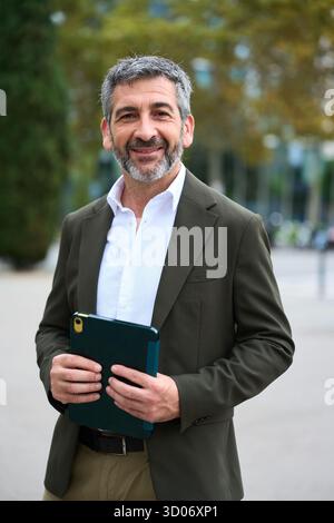 Smiling mature businessman holding tablet in urban setting Stock Photo