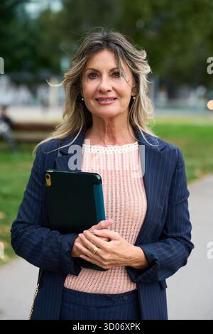 Mature businesswoman holding tablet confidently posing outdoors Stock Photo