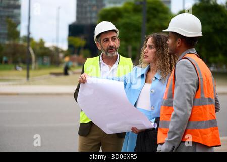 Construction team reviewing blueprint at urban site Stock Photo